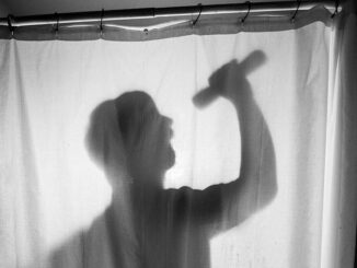 Silhouette of a person singing in the shower with a microphone.