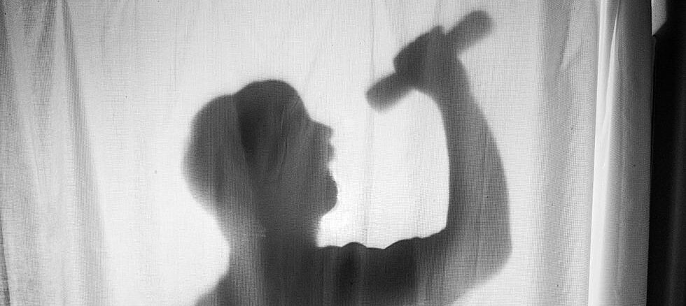 Silhouette of a person singing in the shower with a microphone.